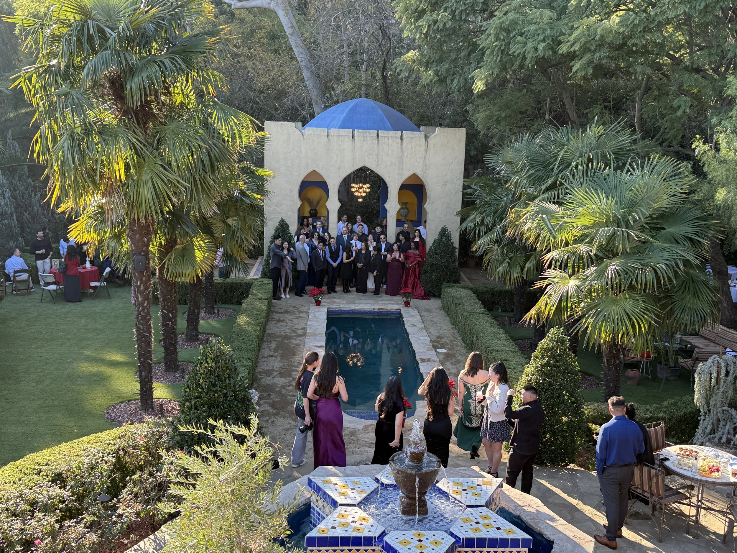 Guests gathered around the blue-tiled pool by the white Moroccan pavilion