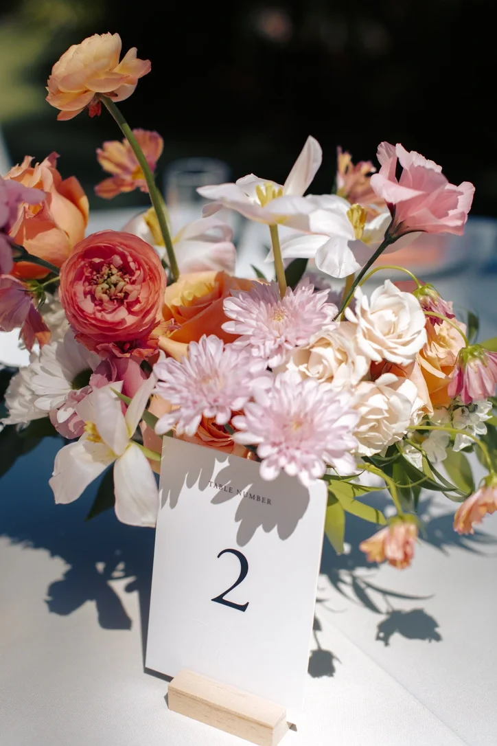 Reception centerpiece of peach and pink blooms beside a table number "2."