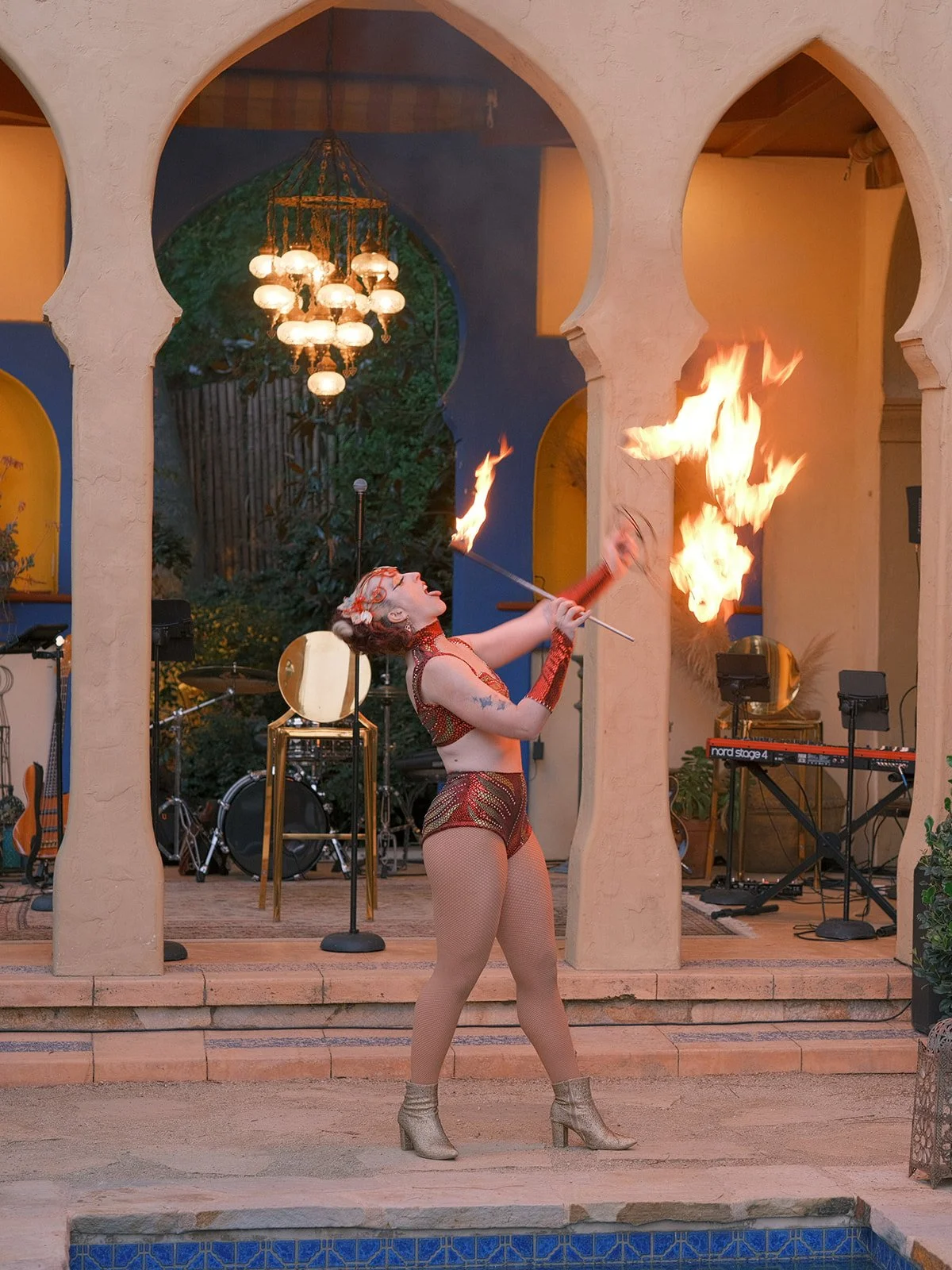 Fire performer holding a flaming torch between cobalt Moroccan columns