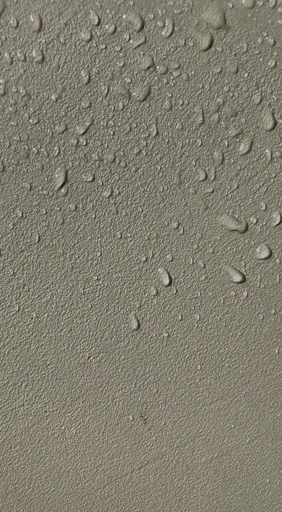 Close-up of a olive microcement finish with water drops showing its subtle handcrafted texture.