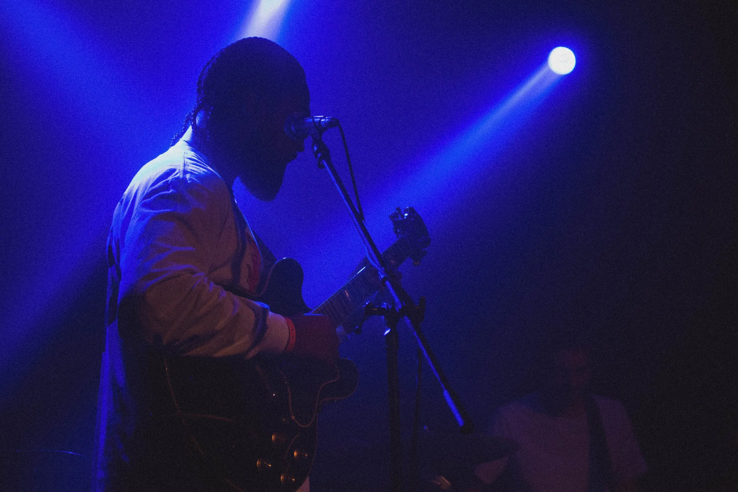 Musicien jouant de la guitare électrique sur scène sous un éclairage bleu