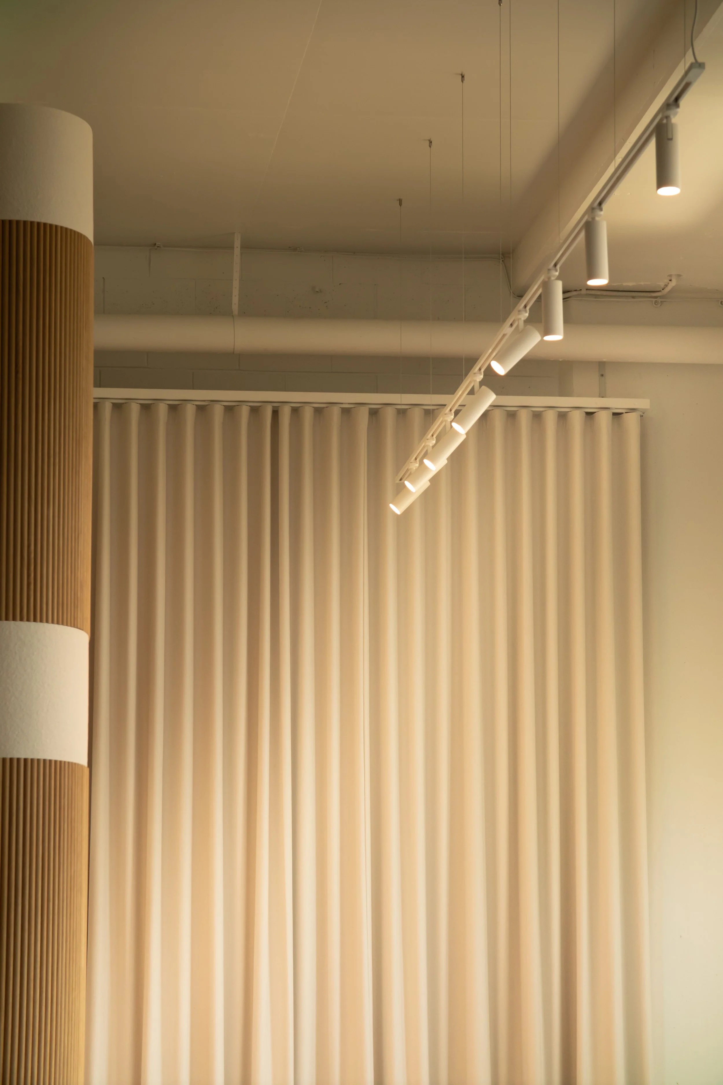 Interior scene with cream-colored curtains and a modern ceiling track lighting system.