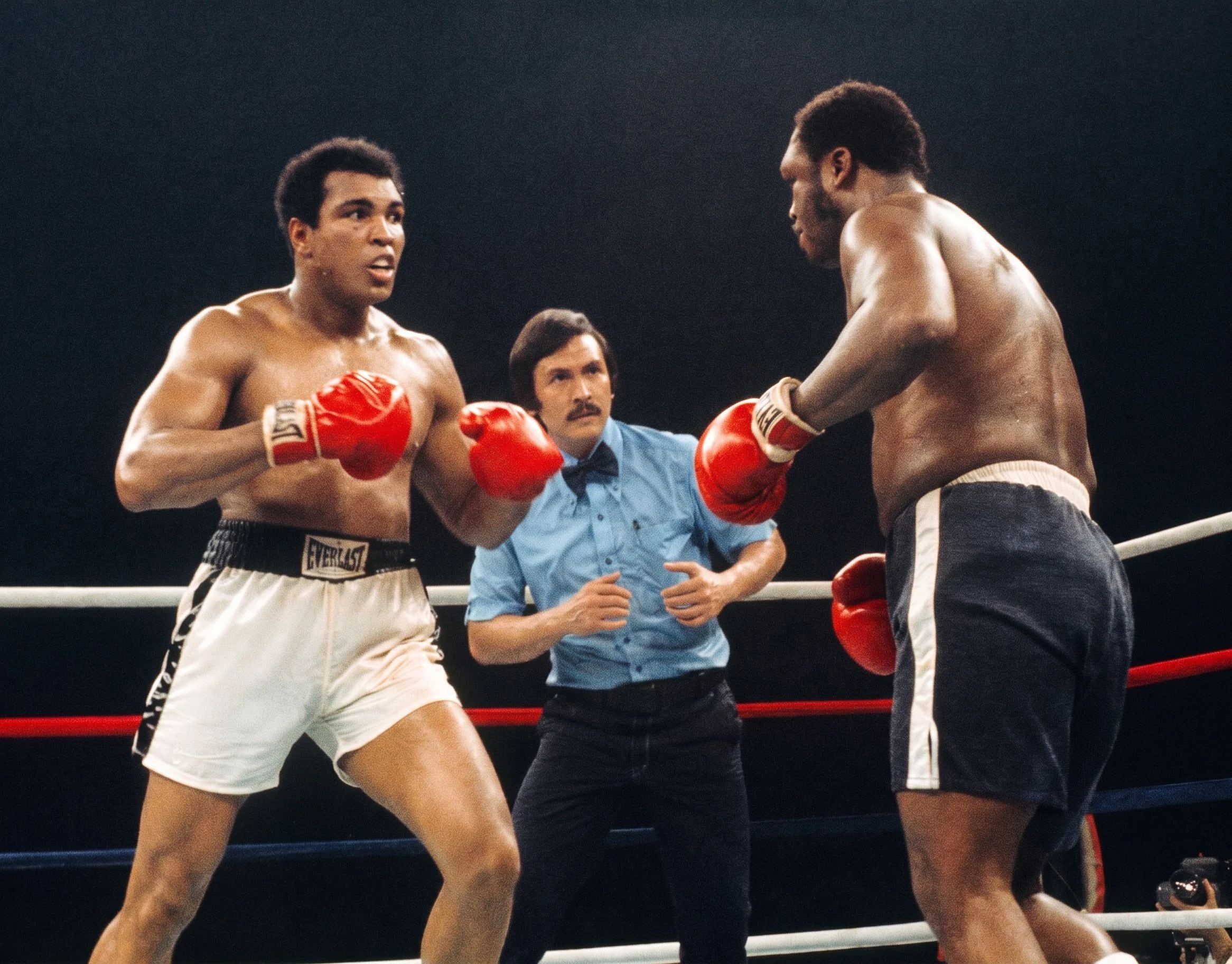 Muhammad Ali watches Joe Frazier’s swollen left eye during the late rounds of the Thrilla in Manila while referee Carlos Padilla looks on.