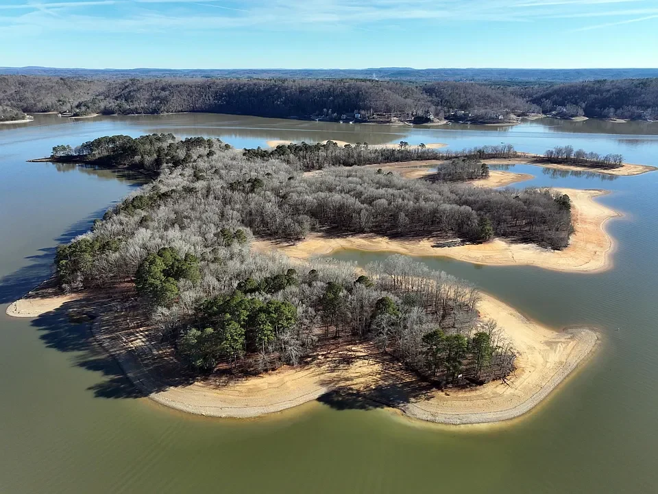 Aerial view of a lake with several tree-covered islands and sandy shores along the water's edge.