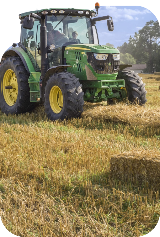 Green John Deere tractor working in a harvest field during daytime.