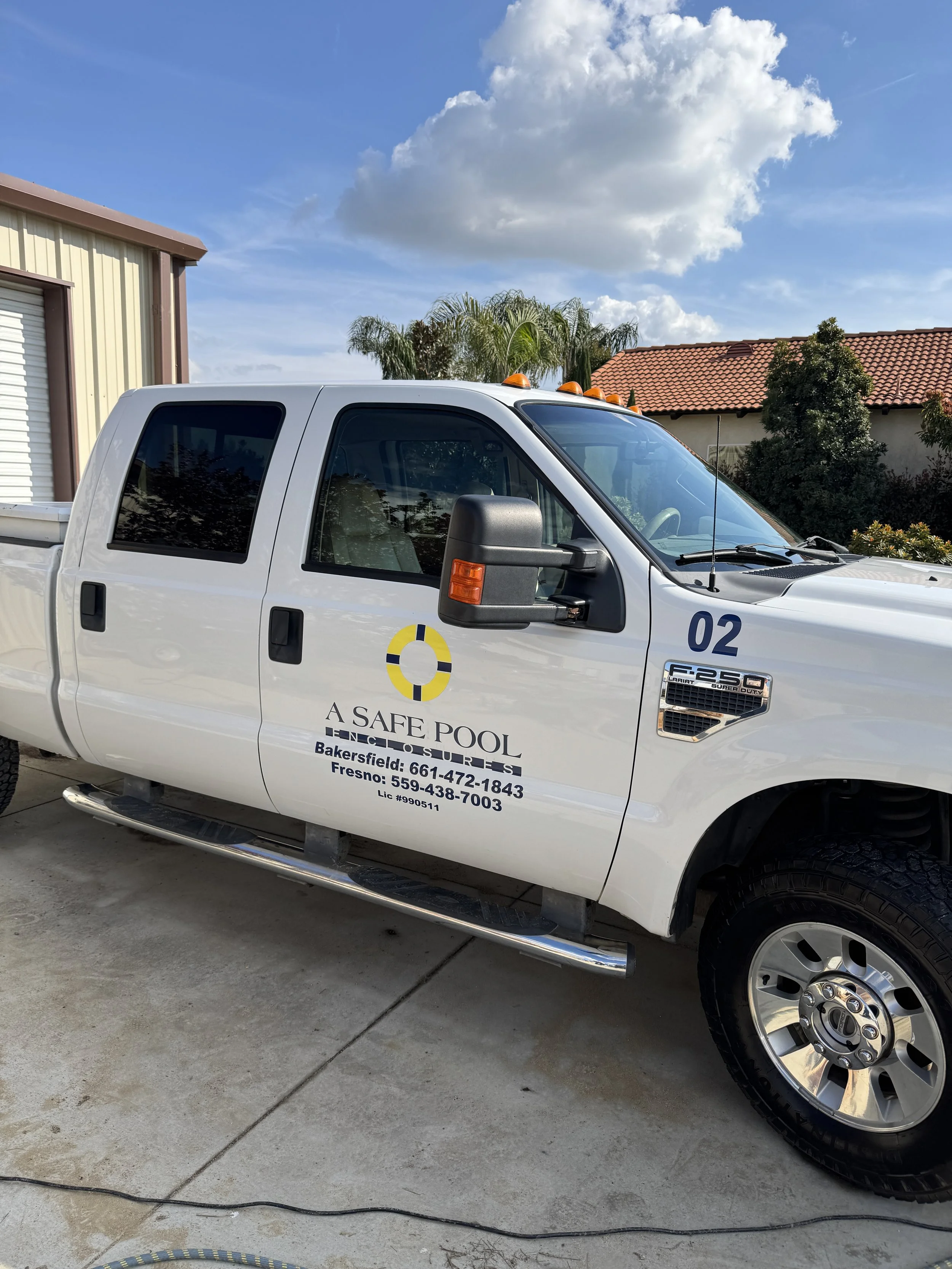 White pickup truck with logo and contact information for A Safe Pool, a pool inspection service, parked on a concrete driveway.