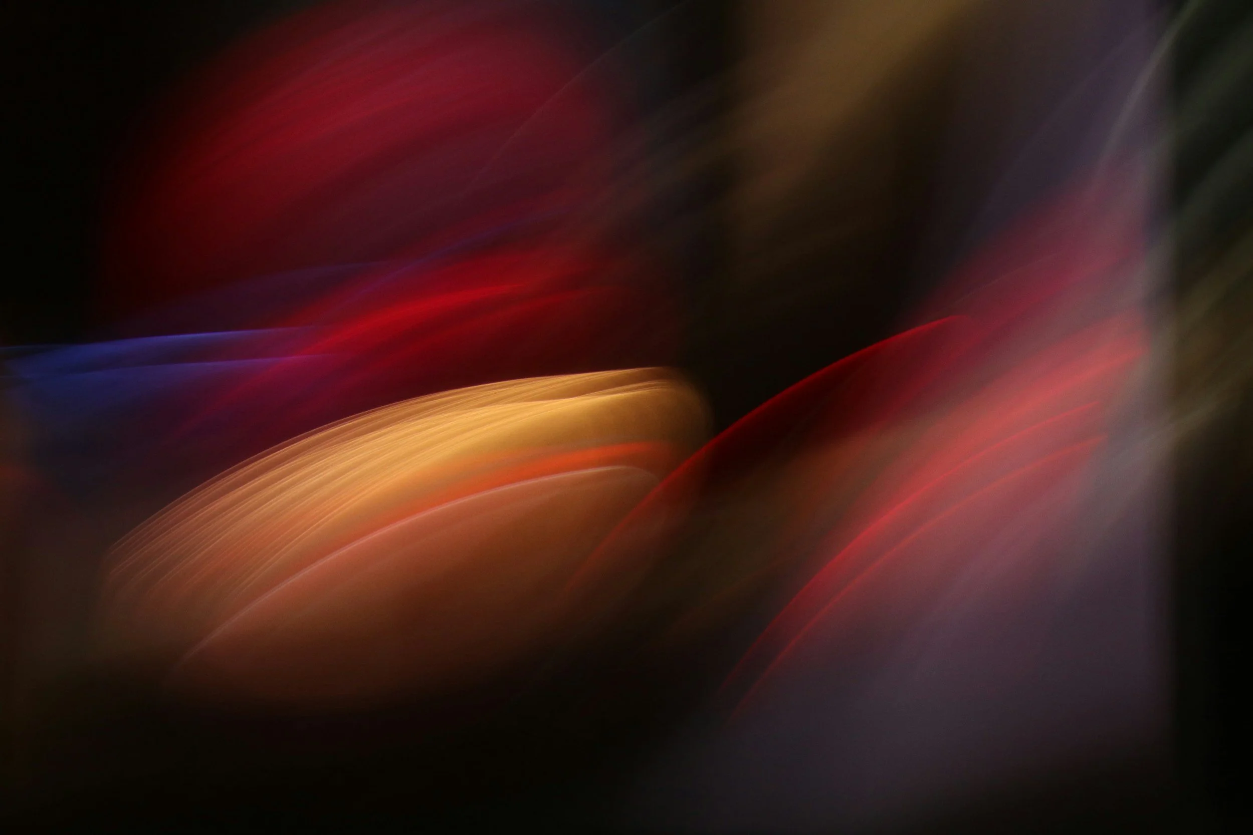 Abstract blurred colorful lights with red, purple, yellow, and blue hues on a dark background.