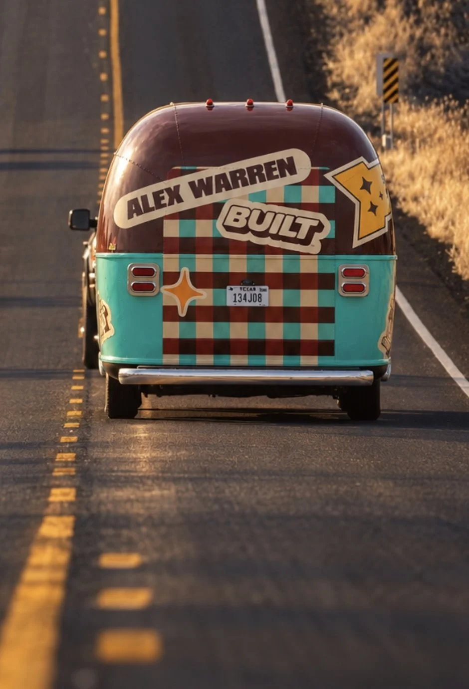 Built x Alex Warren camper rolling down an open two-lane highway at golden hour