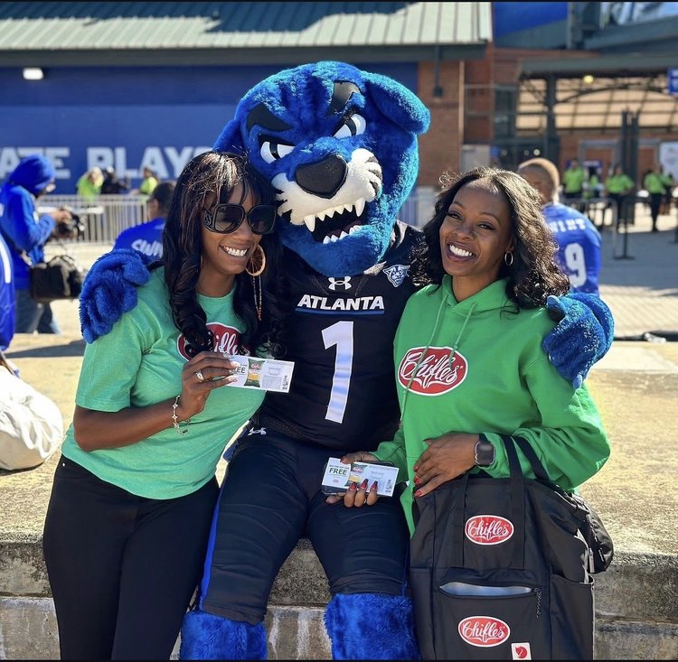 Chifles ambassadors posing with a team mascot at a game-day event