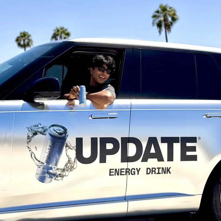 UPDATE Energy Drink ambassador holding out a can from the window of an UPDATE-wrapped Range Rover under palm trees