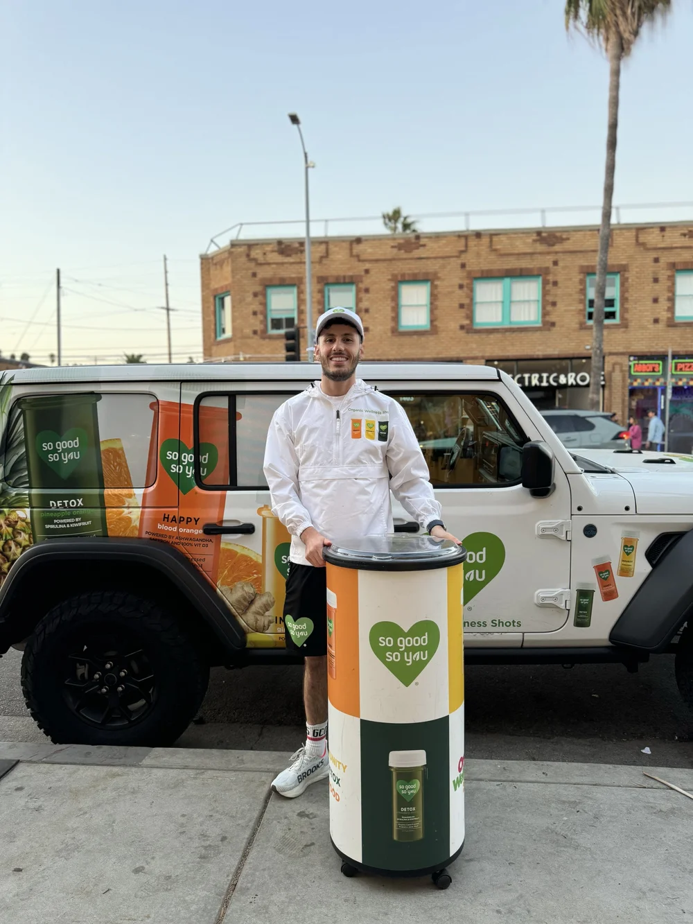 So Good So You brand ambassador with a sampling station beside a branded jeep on a city street