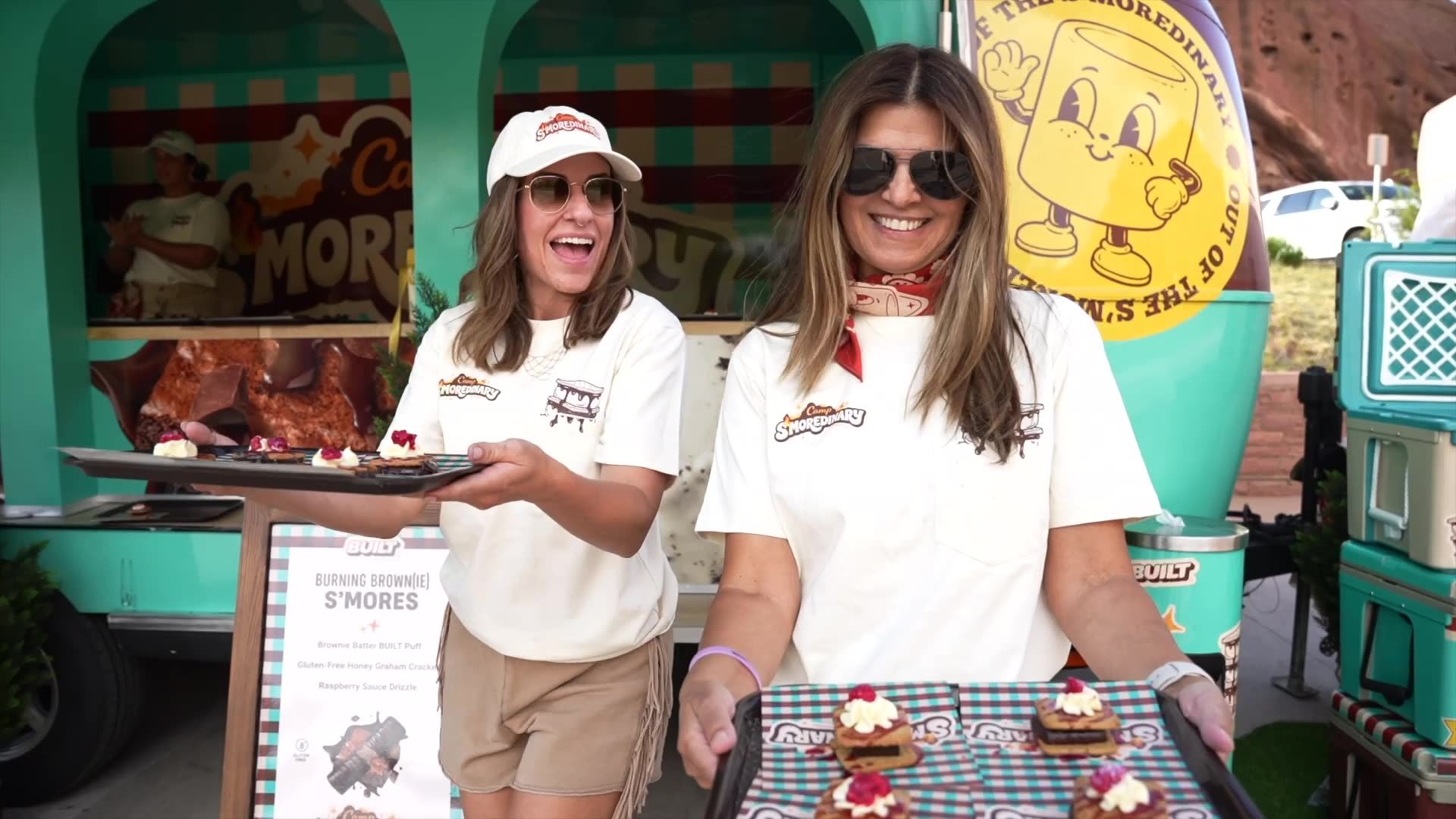 Front & Center brand ambassadors holding trays of s&rsquo;mores samples in front of the Camp S&rsquo;moredinary Airstream on the Built x Alex Warren tour