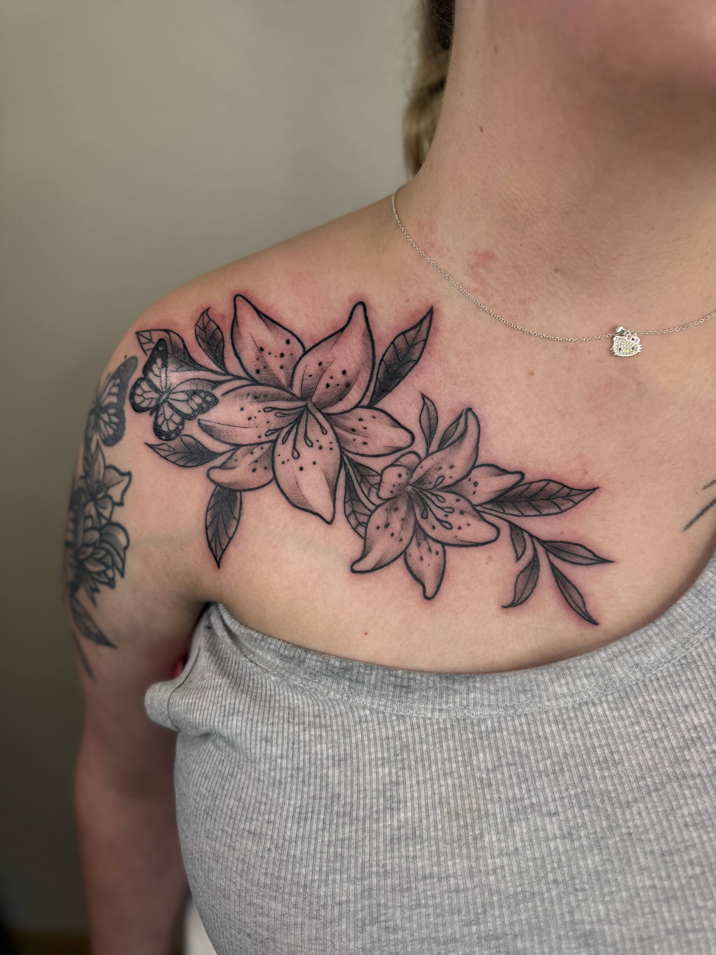 Black and gray lily and butterfly tattoo on chest and shoulder, Lago Vista TX