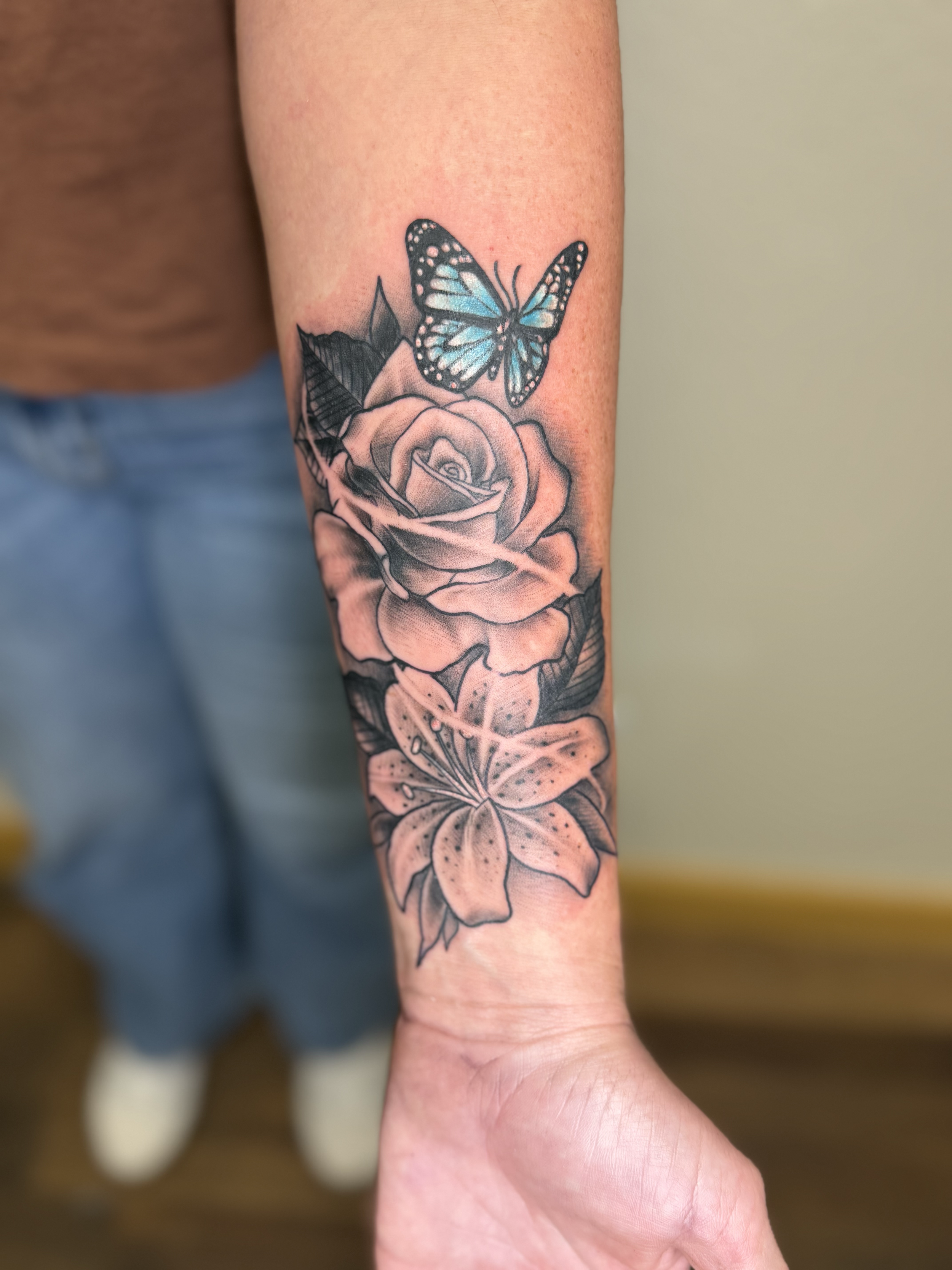 Rose, lily, and blue butterfly tattoo on forearm, Lago Vista TX