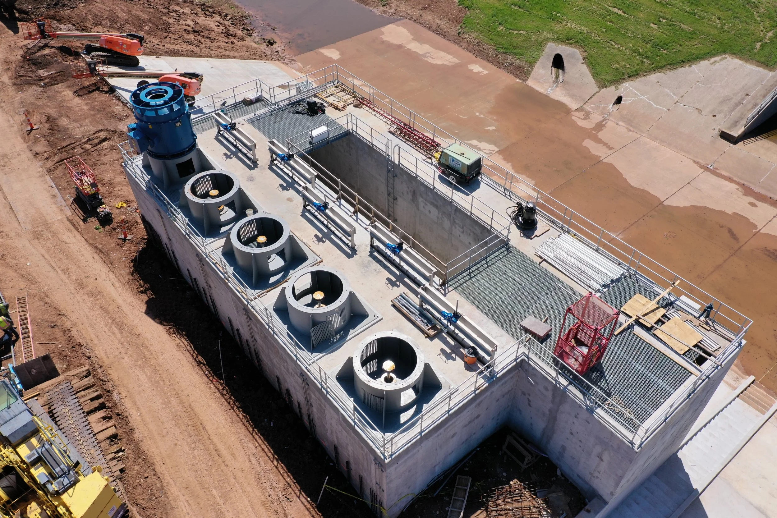 An aerial view of a large industrial building under construction with visible HVAC units on the roof, construction equipment, and scaffolding.