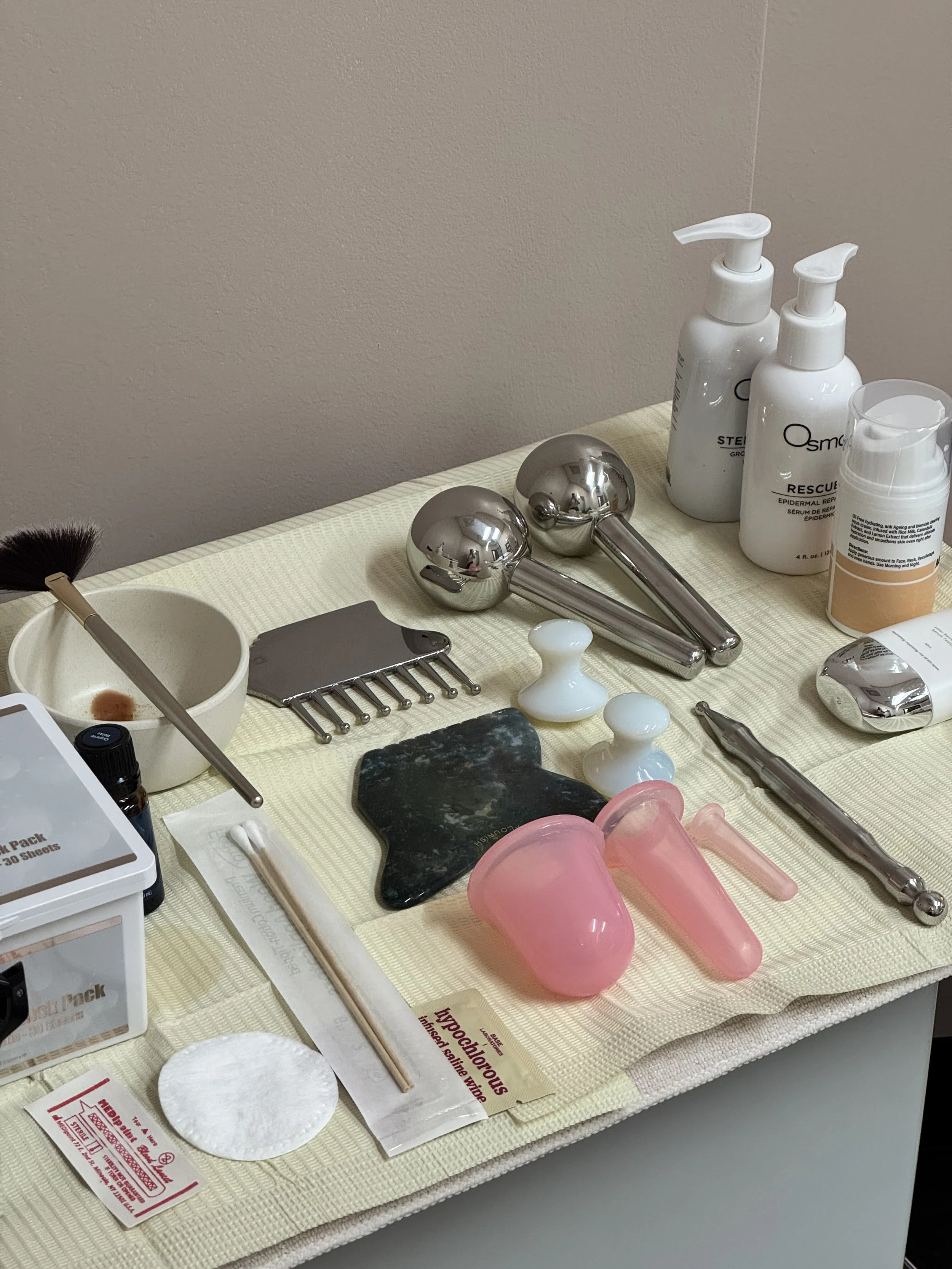 Lymphatic drainage and sculpting facial set up with clean skincare products, gold globes, gua sha stone, facial cupping in Denver, Colorado