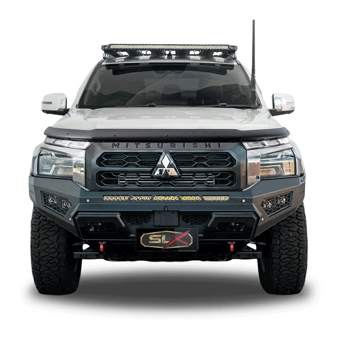 Front view of a rugged Mitsubishi off-road vehicle with modifications like a roof rack, large tires, and a removable black hood protector.