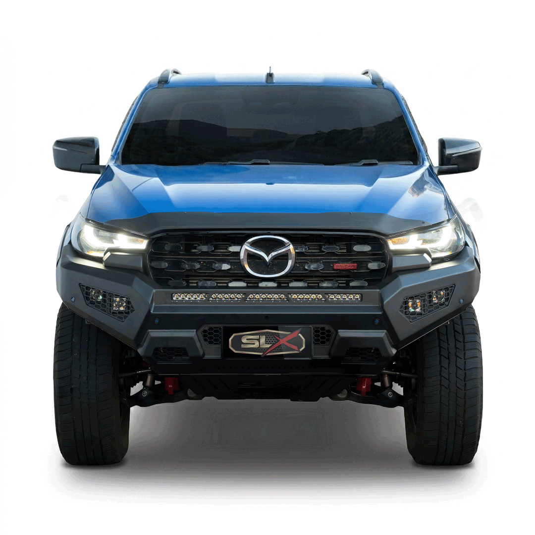 Front view of a blue Mazda pickup truck with a black grille, LED headlights, and off-road tires.