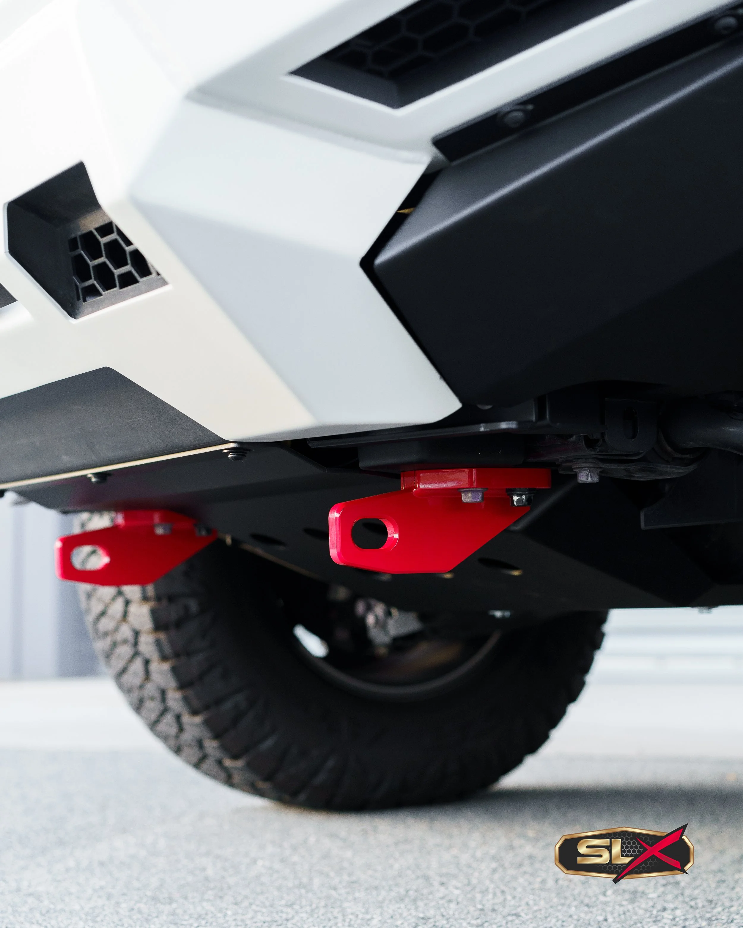 Close-up view of the underside of a vehicle showing a red recovery hook and a large off-road tire.