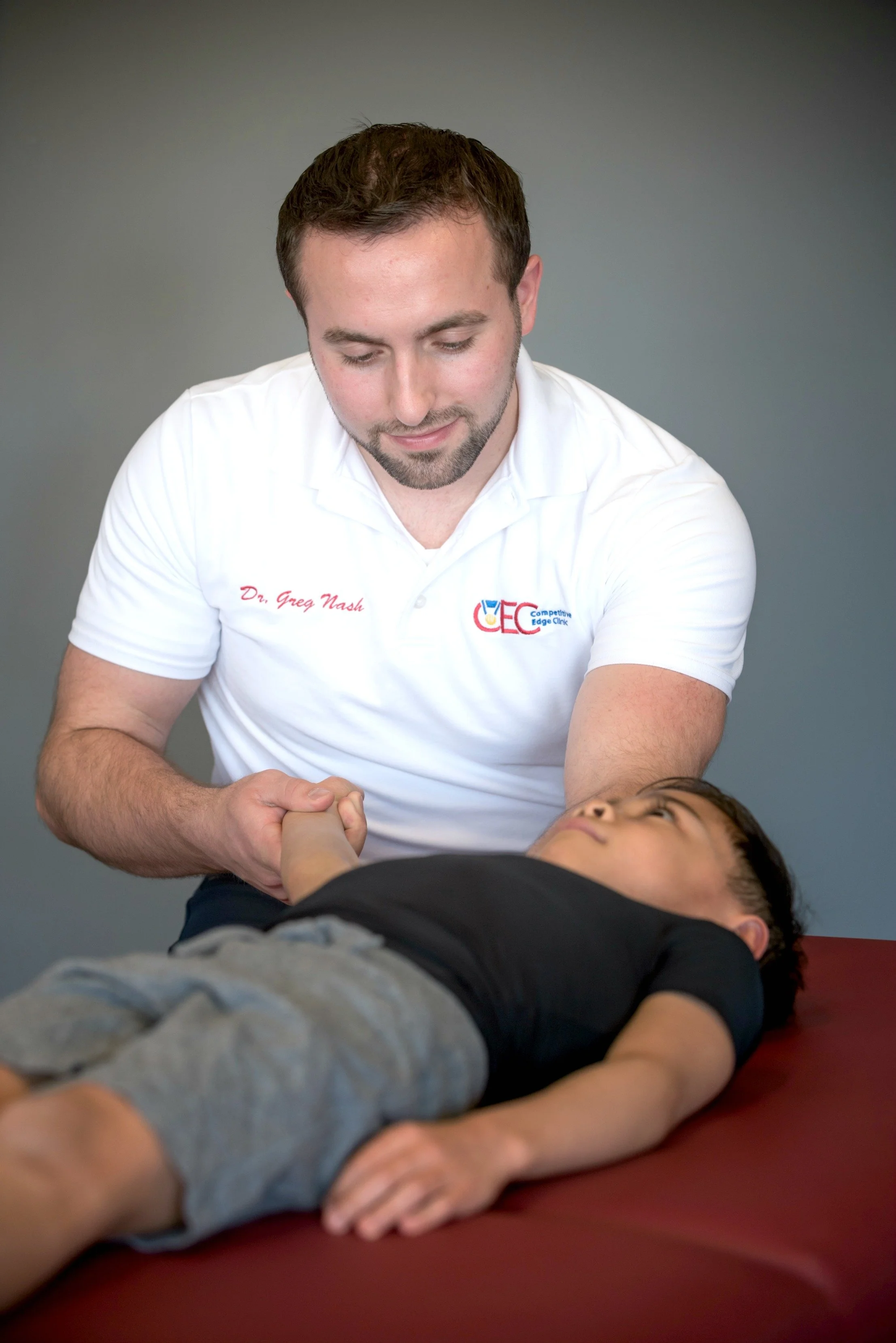 A doctor performs a medical examination on a young boy lying on an examination table.