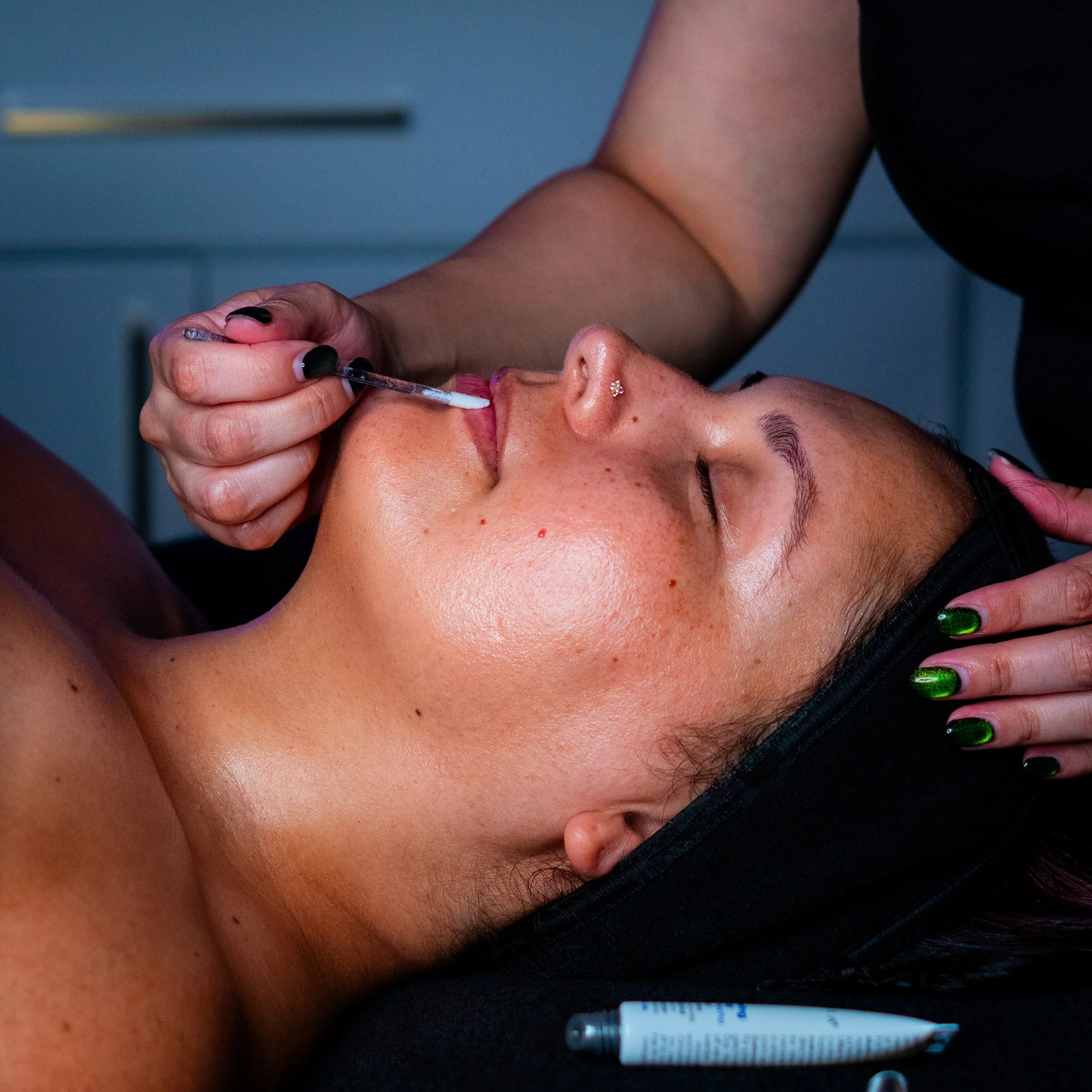 Lip balm being applied during a facial treatment.