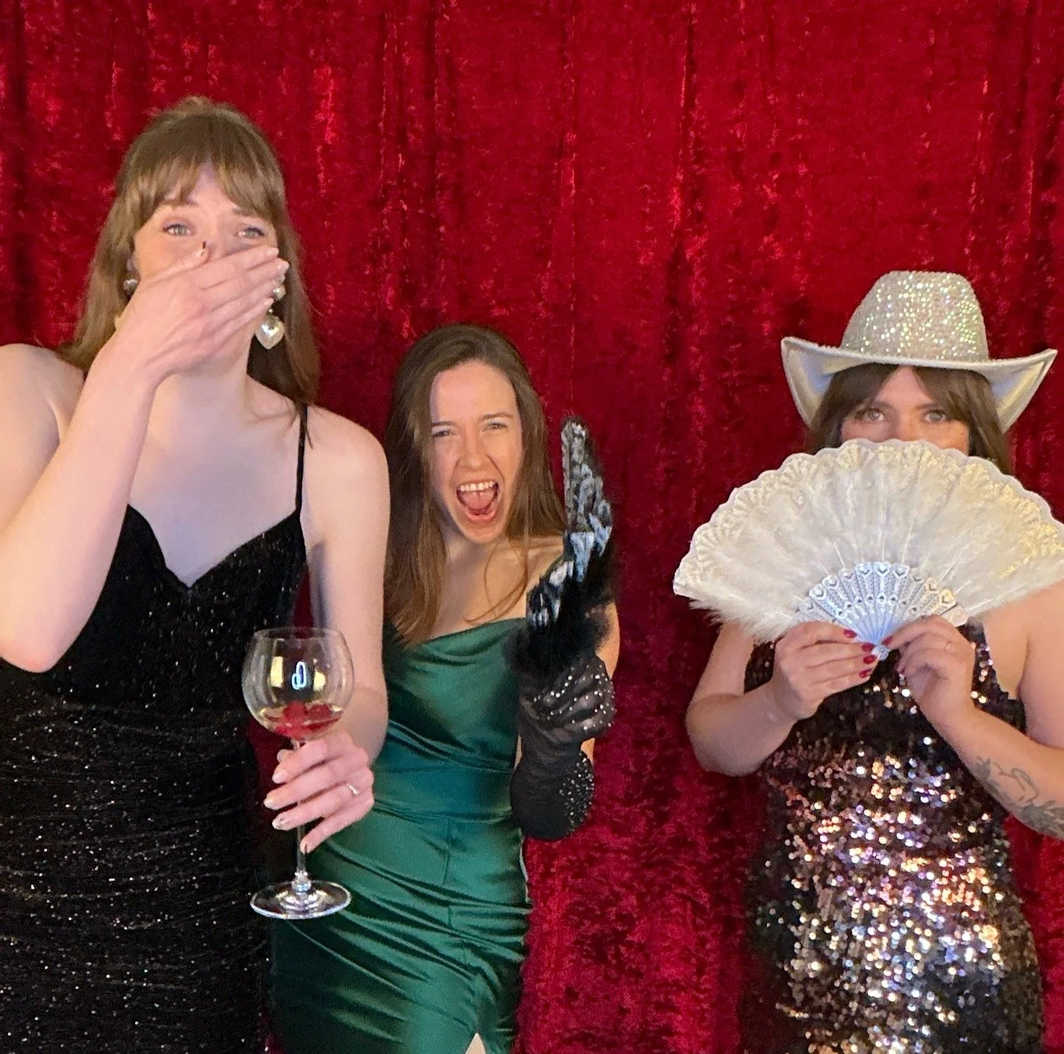 Guests laughing and posing in front of a red backdrop at a Nashville wedding photo booth rental, fun and interactive reception entertainment