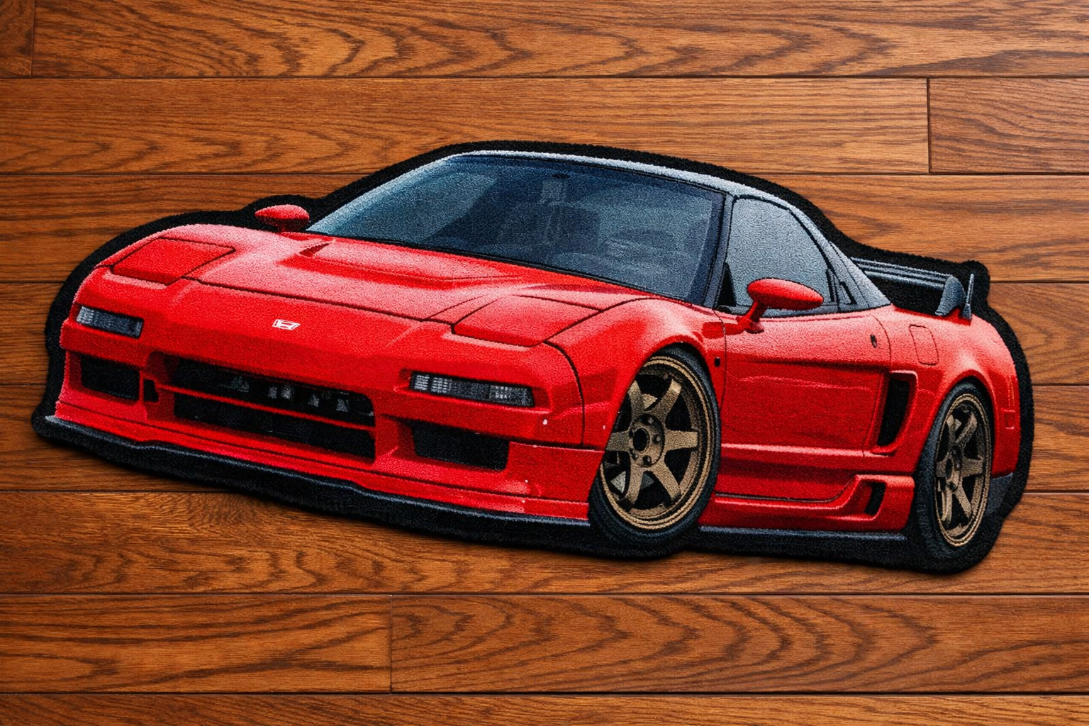 A sticker of a red sports car with black details on a wooden surface.