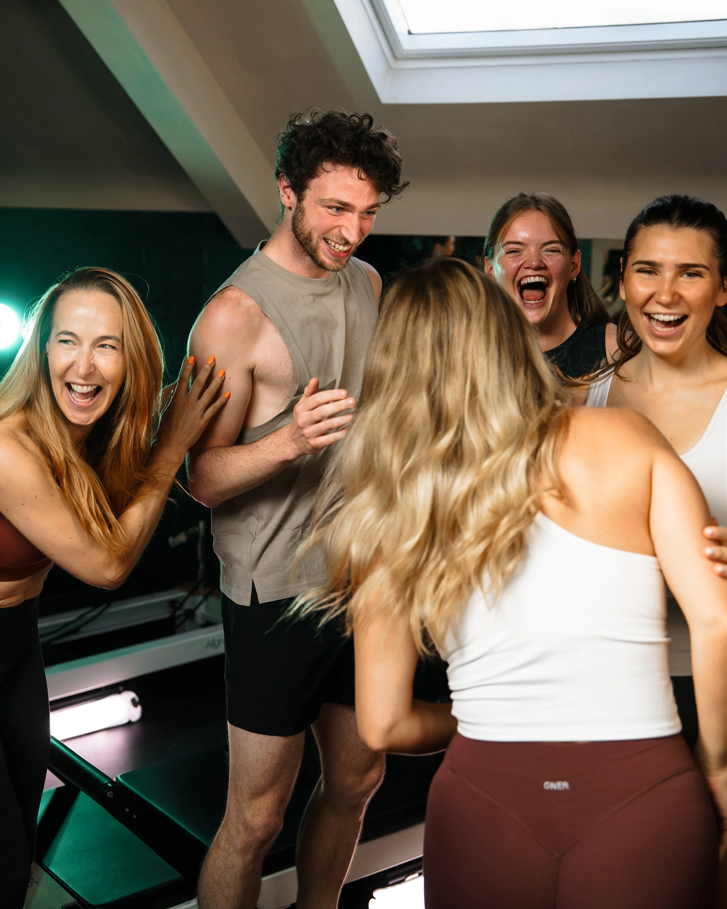 A group of people smiling and laughing after a Pilates class