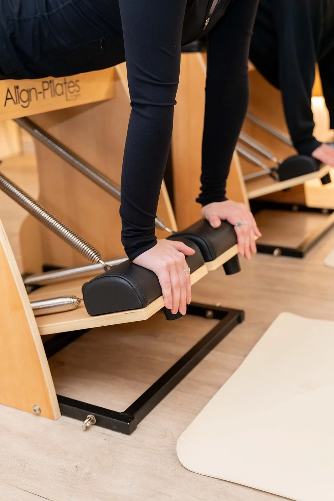 Person performing Pilates exercises on a reformer machine in a fitness studio
