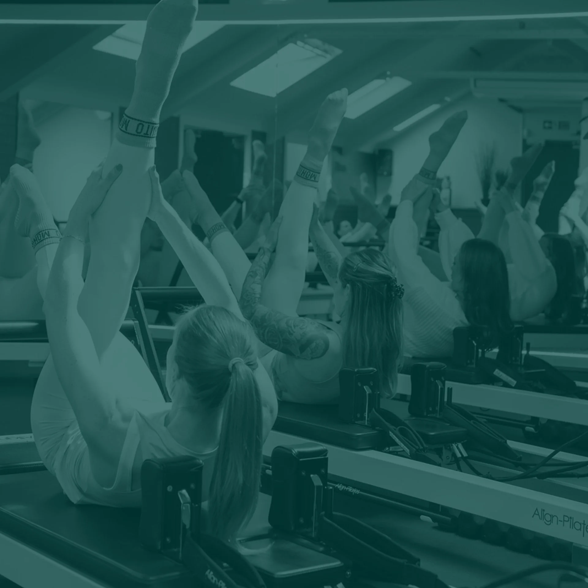 Group of people participating in a Pilates class on reformer machines in a fitness studio.