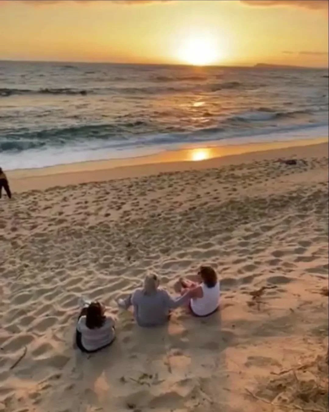 Three women sitting at the beach watching the sunset on the bass coast.
