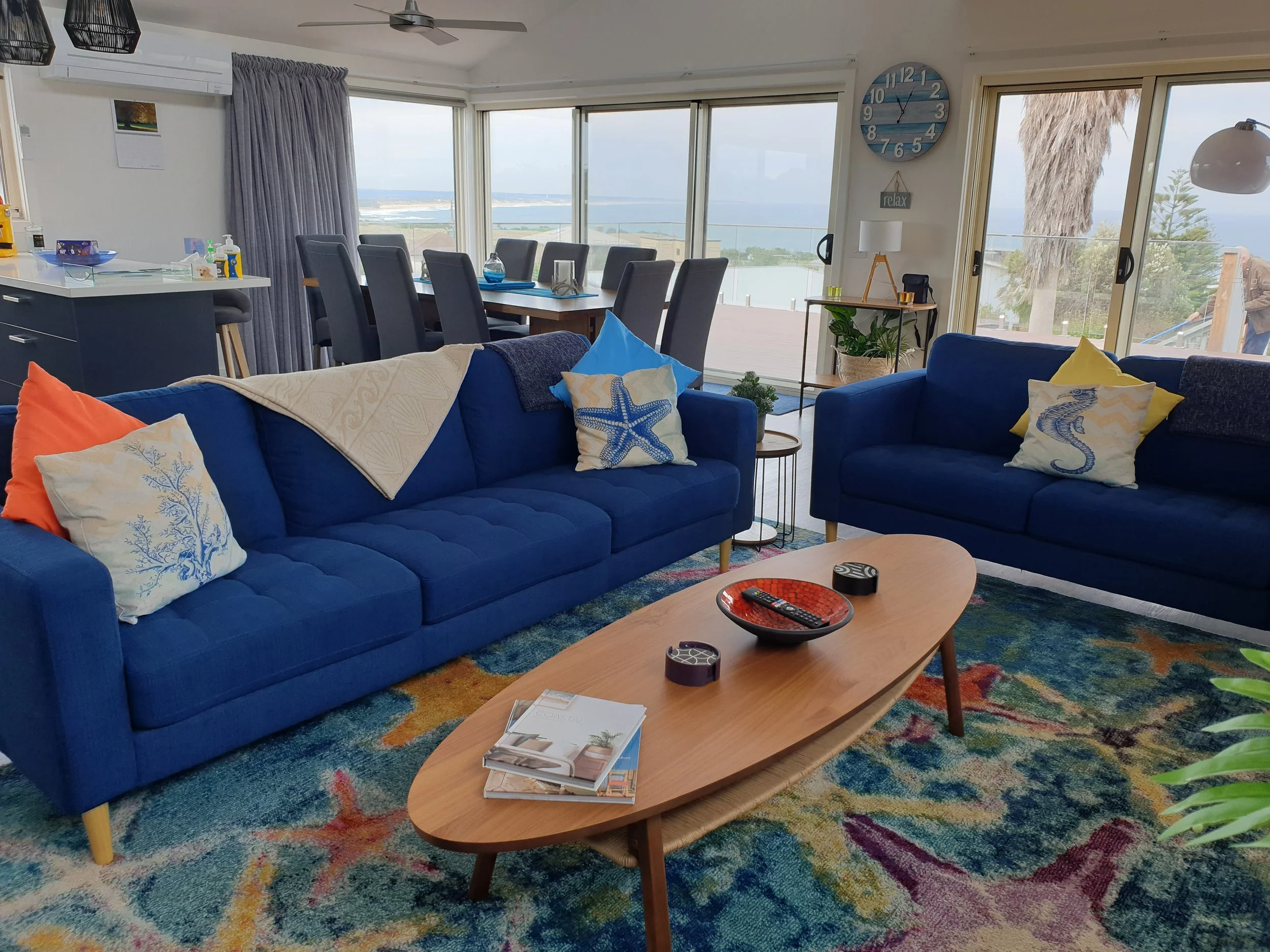A view of the loungeroom upstairs featuring two blue couches and an oval coffee table.