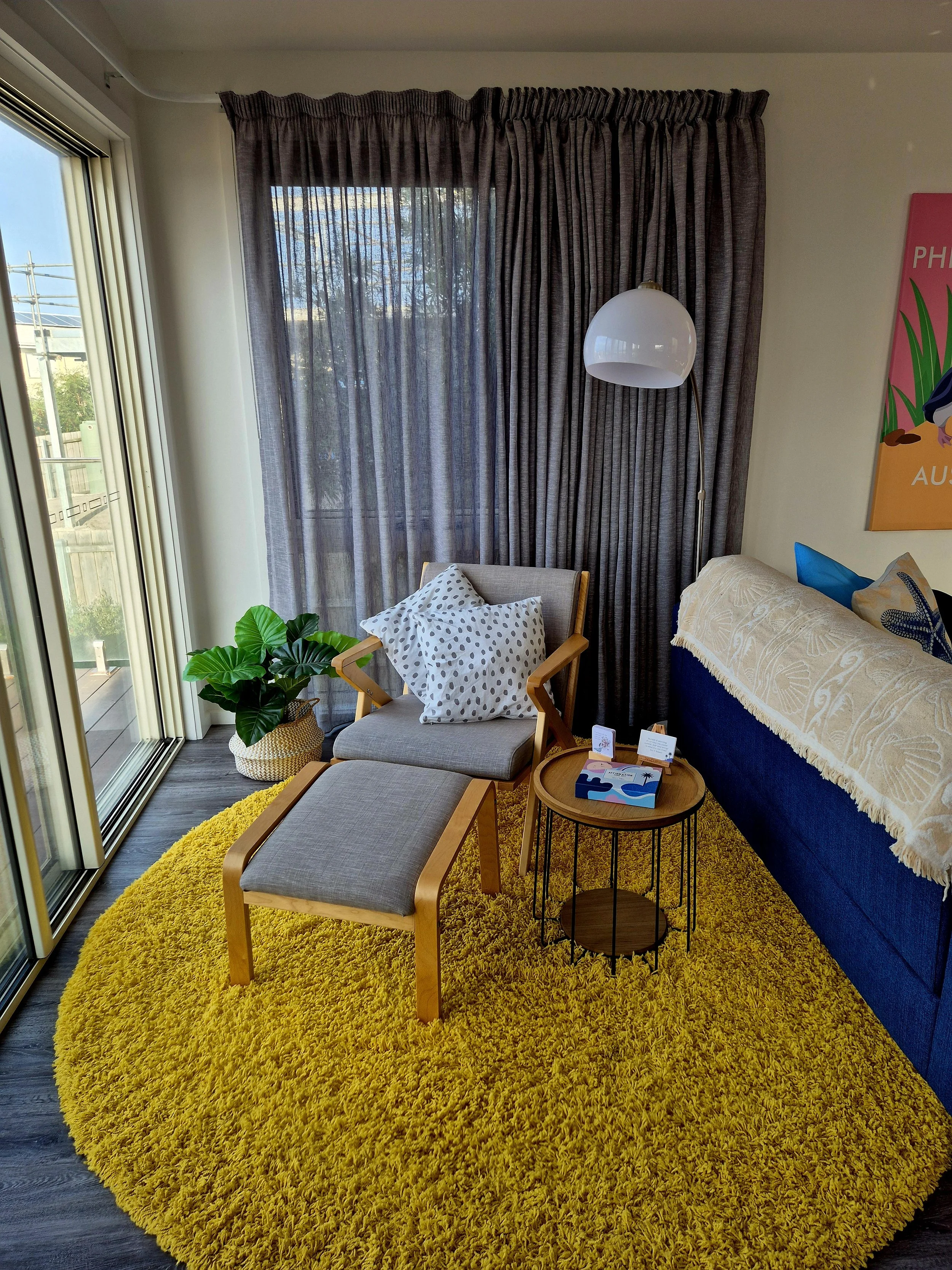 A front on view of a sitting chair in the corner with matching footrest and sidetable.