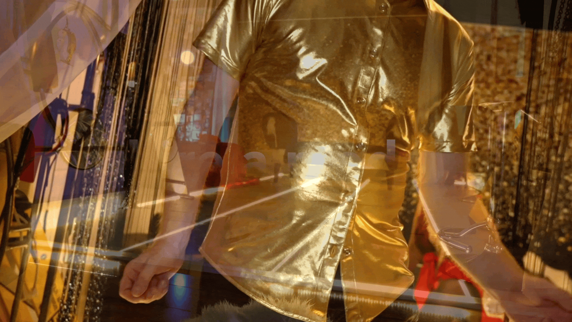 A person wearing a shiny gold-colored shirt walking past a display of jewelry and accessories in a store.