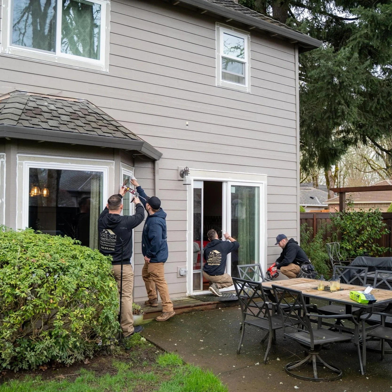 Home exterior inspection with contractors and homeowners, showing importance of checking gutters, trim, and moisture damage after winter to prevent expensive repairs.