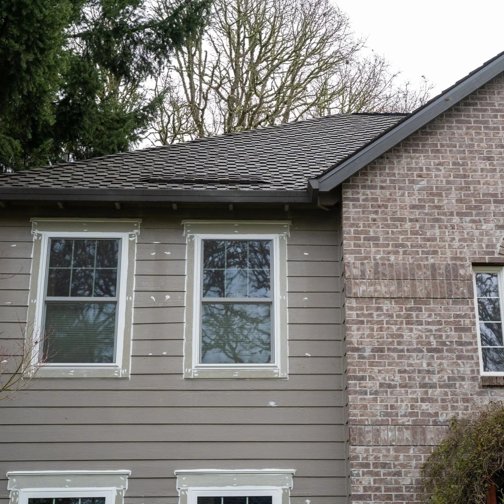 Residential roof with curling asphalt shingles and granule deterioration, illustrating common roofing damage caused by prolonged wet climate exposure.