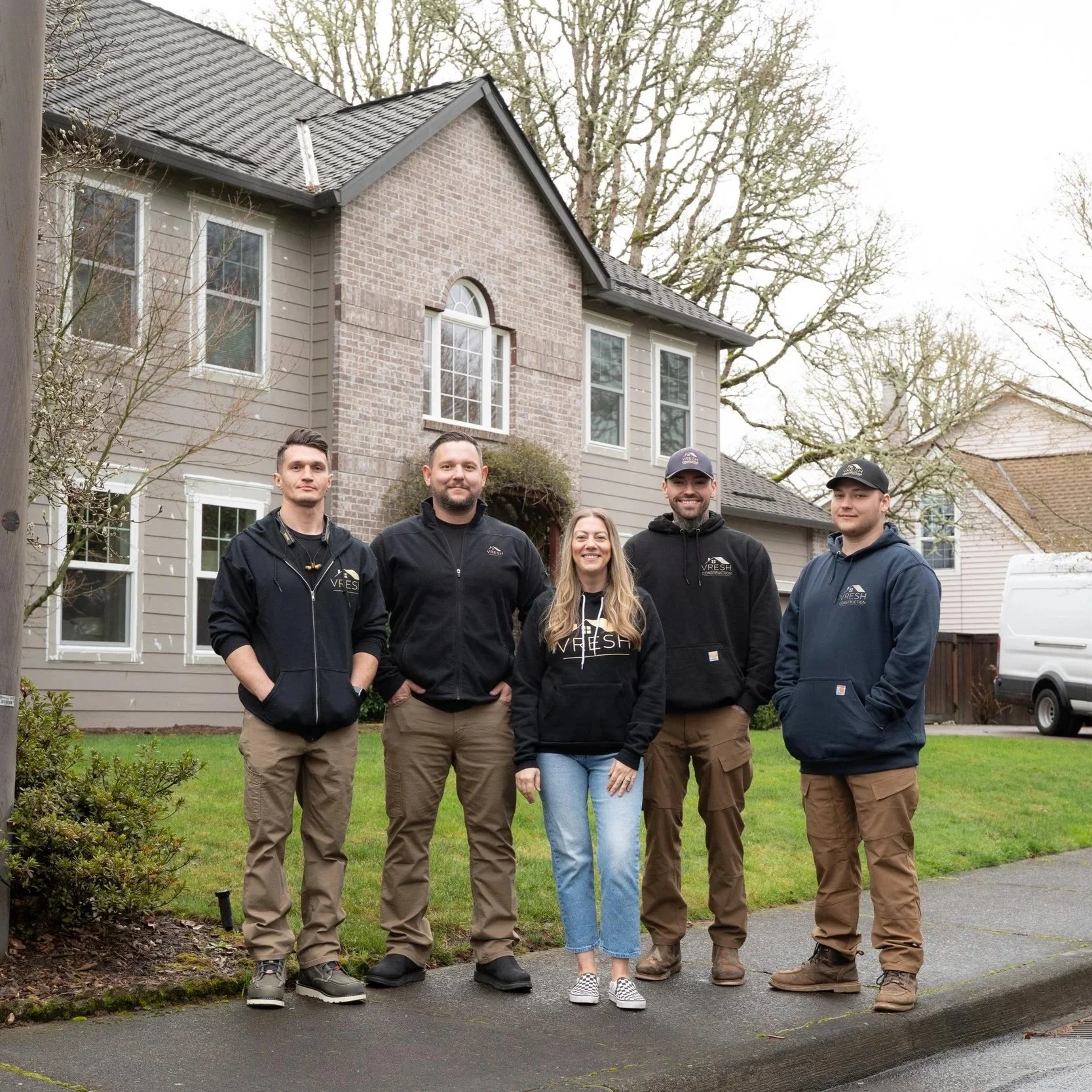Exterior painting team posing beside residential property while preparing for Portland house repainting project involving detailed surface preparation work.