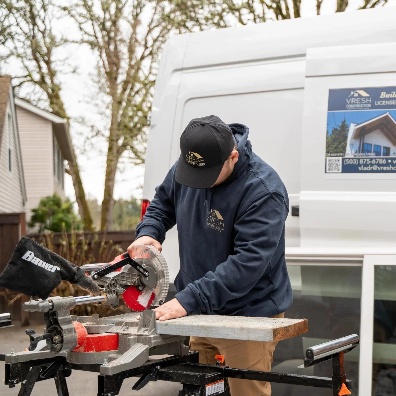 Construction worker preparing basement renovation materials near company van for Portland project involving egress windows, permits, and moisture protection systems.