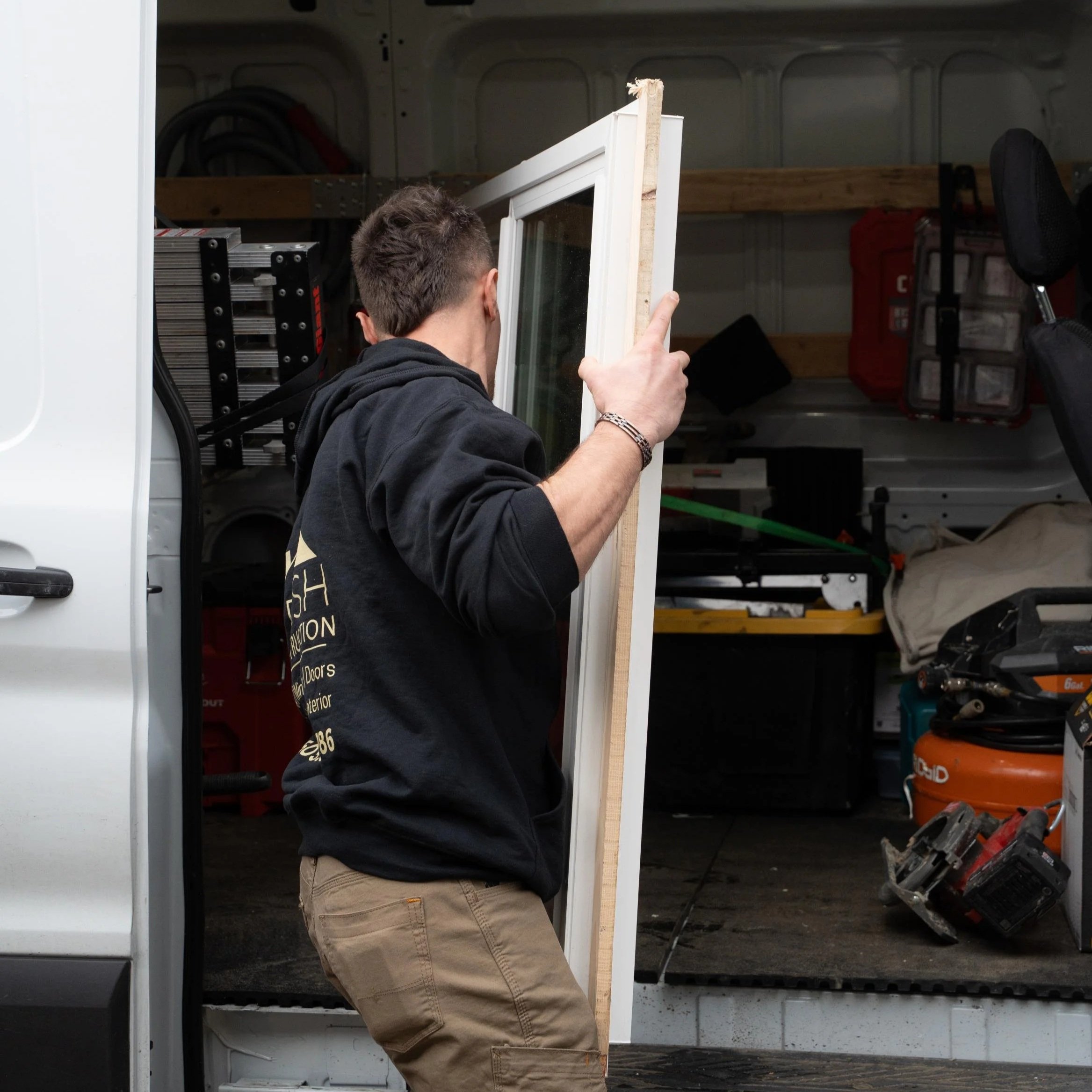 Contractor carrying construction materials into garage, symbolizing bathroom renovation work and varying project scopes from basic updates to full remodels with structural changes.