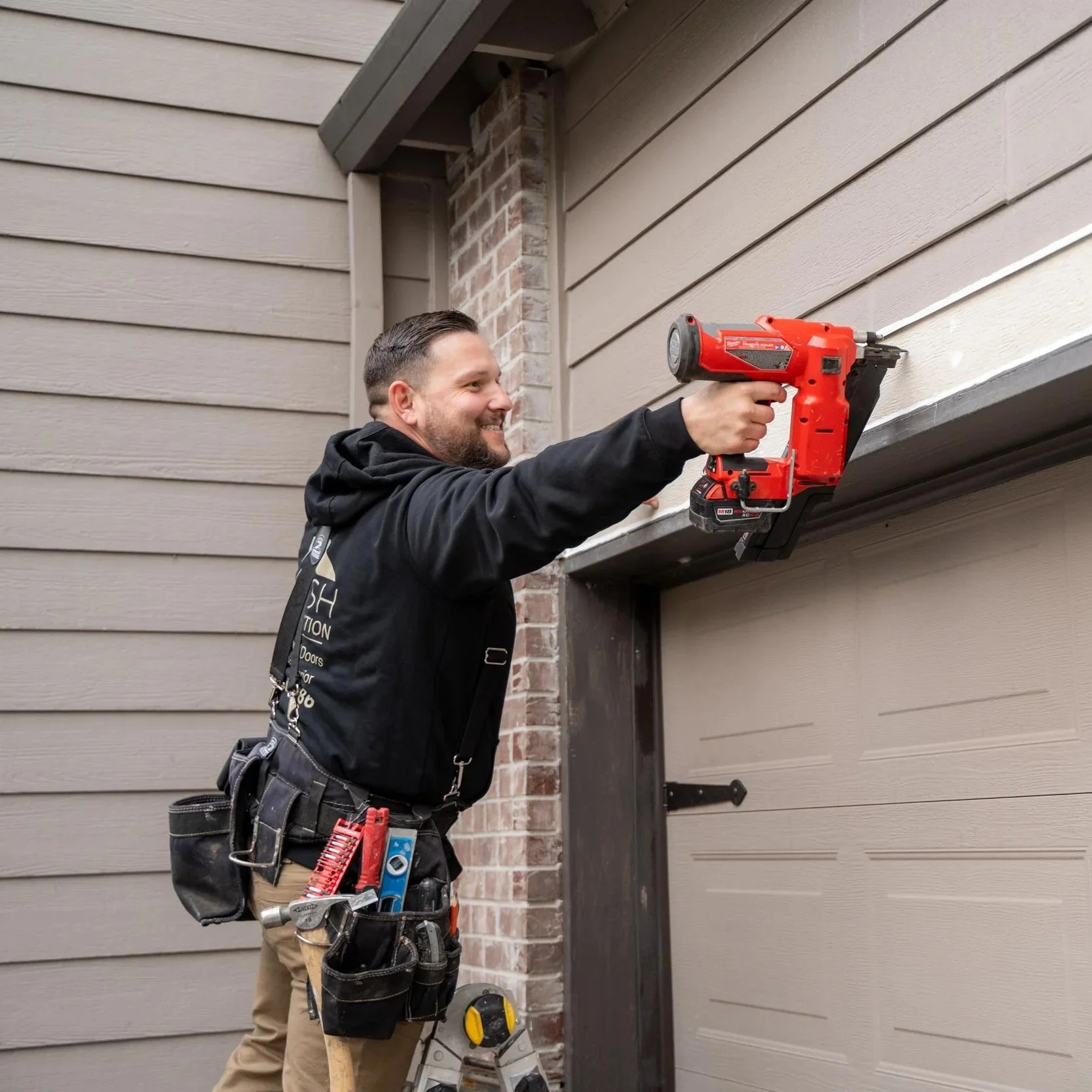 Contractor using power nailer for exterior dry rot repair on garage trim during Portland structural wood restoration project work.