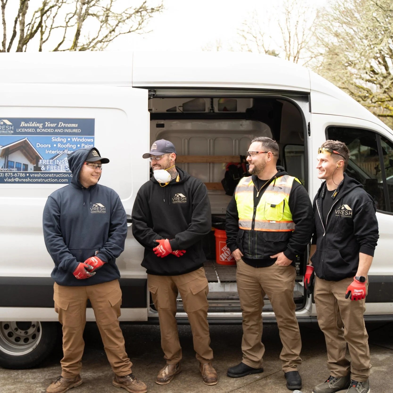 Construction team standing beside work van during consultation about basement bedroom egress windows and Portland legal safety requirements.