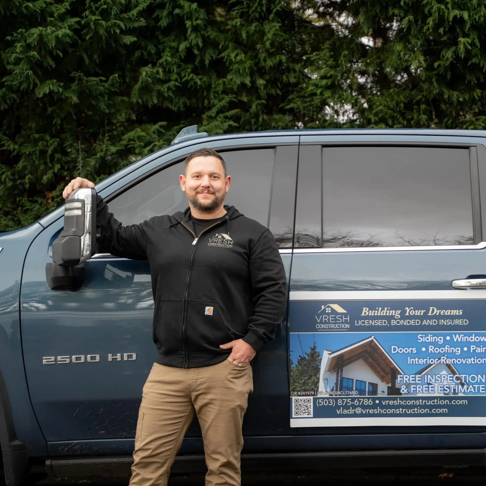 Contractor standing next to branded work truck, symbolizing professional installation services like egress windows that convert basement space into valuable, livable square footage.