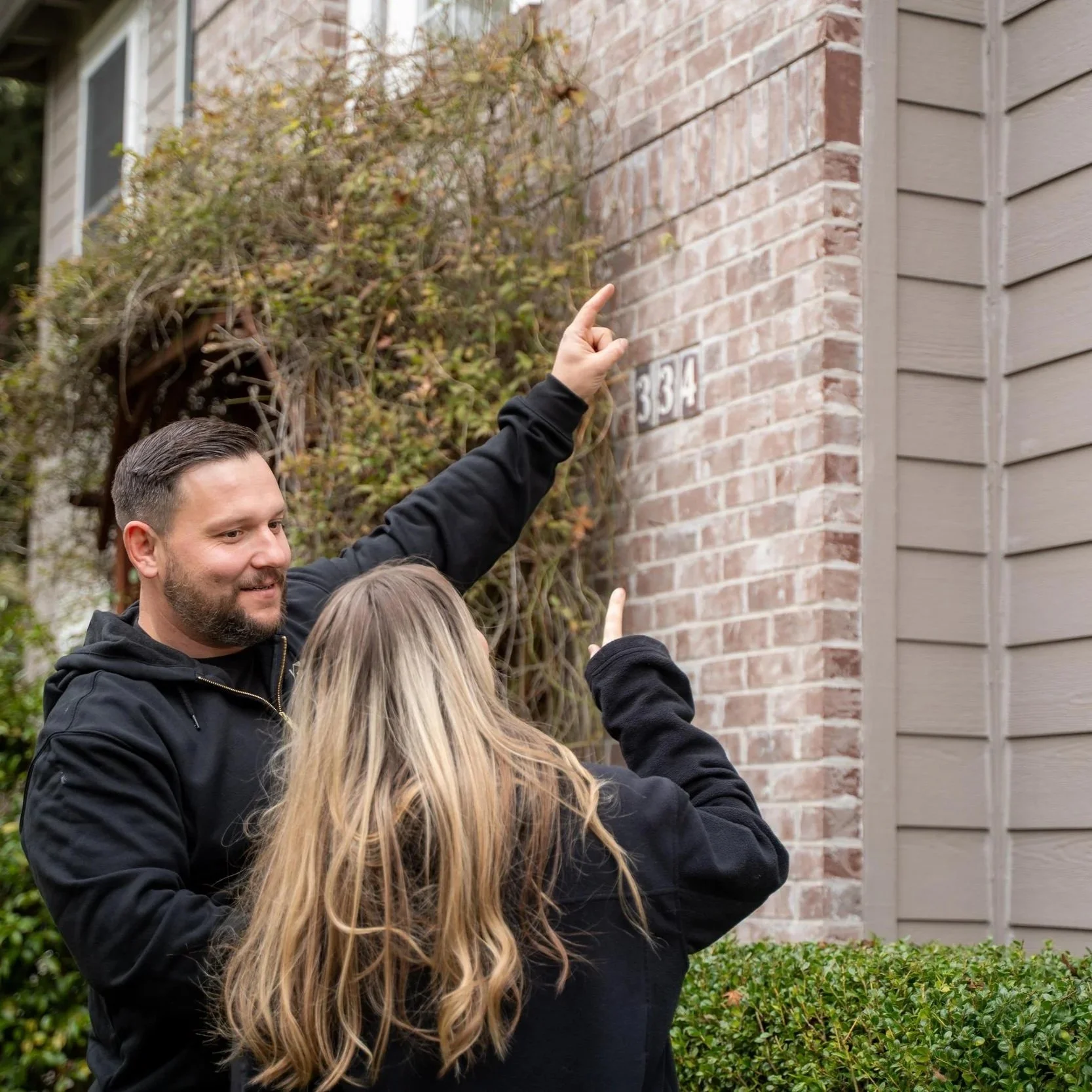 Contractor discussing exterior siding with homeowners, showing importance of understanding scope differences affecting Hardie siding project costs, including trim, prep work, and materials.