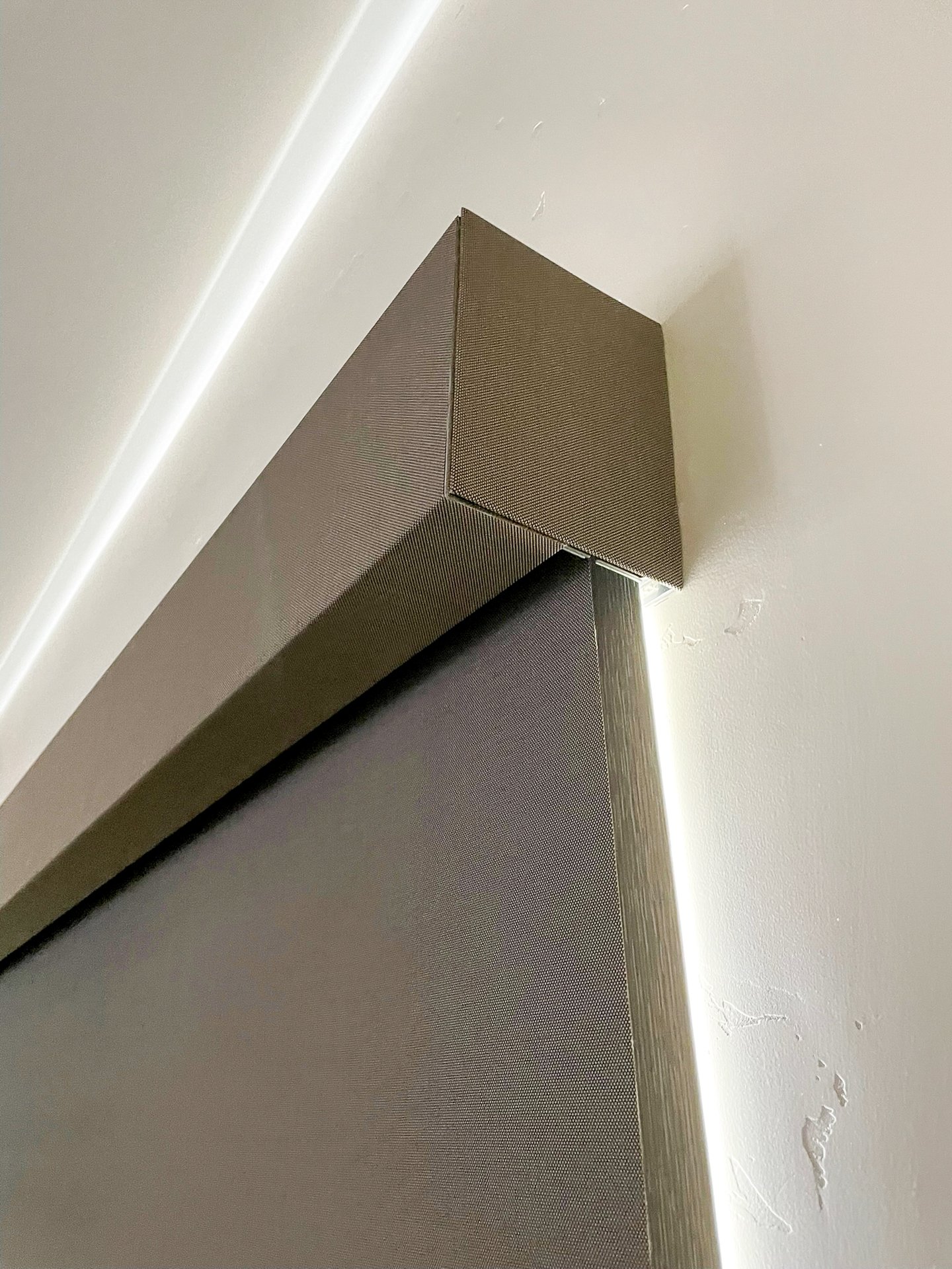 Close-up photo of a modern, metallic piece of furniture or fixture, possibly a cabinet or wall panel, with clean lines and a textured surface.