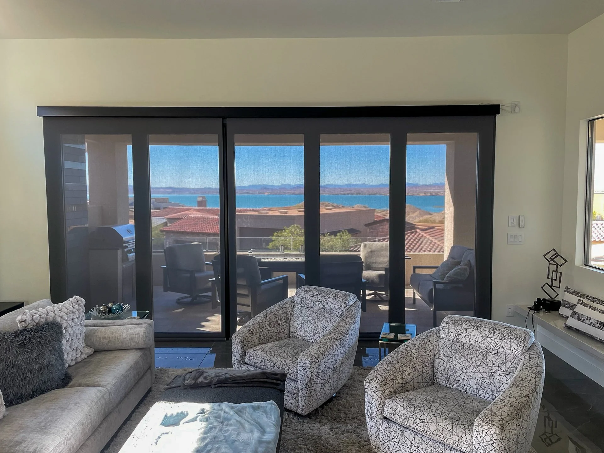 Living room with large sliding glass doors leading to a balcony overlooking a view of water, houses, and distant mountains.