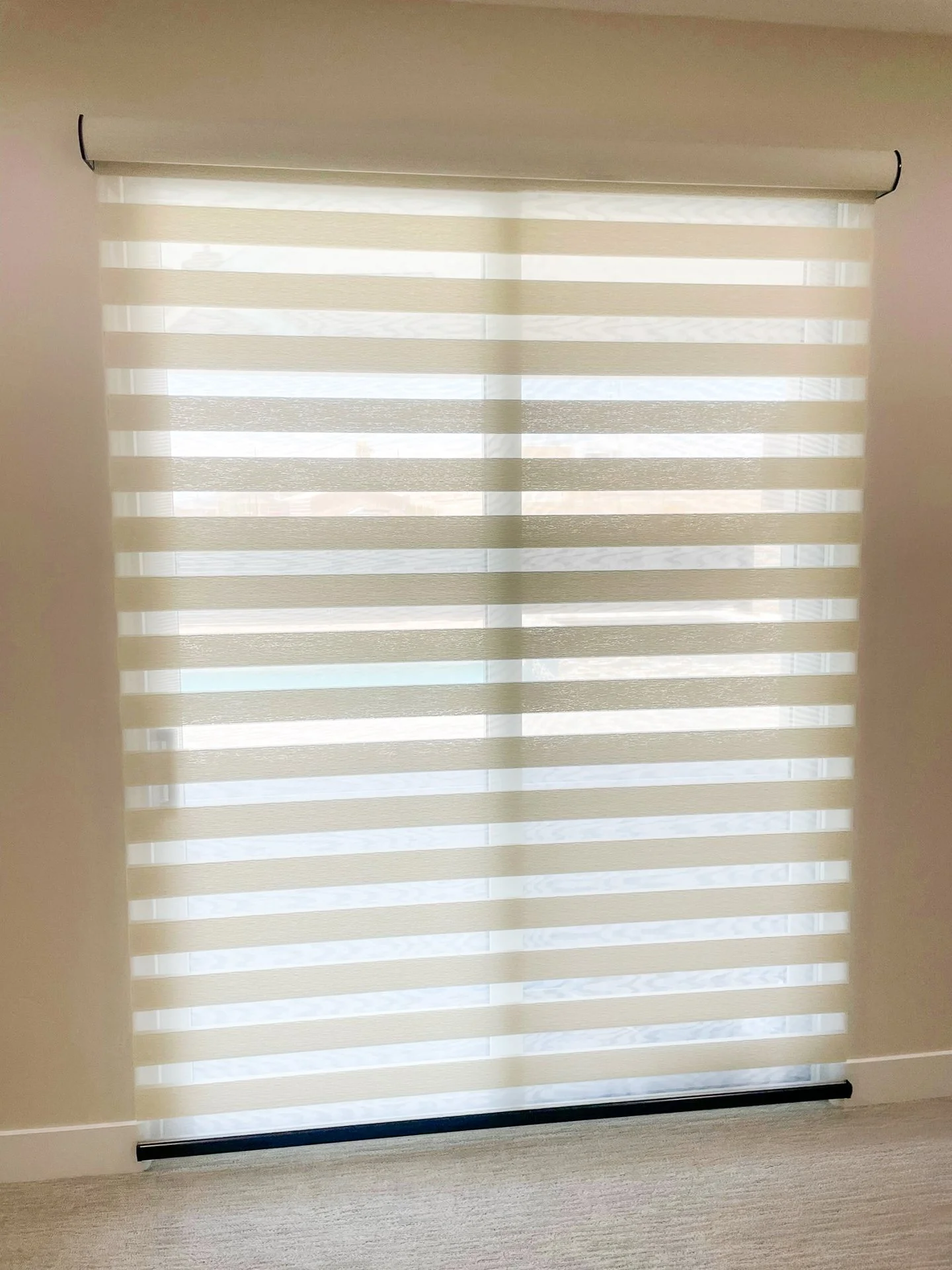 A window with horizontal blinds, partially open, allowing light to filter into the room.