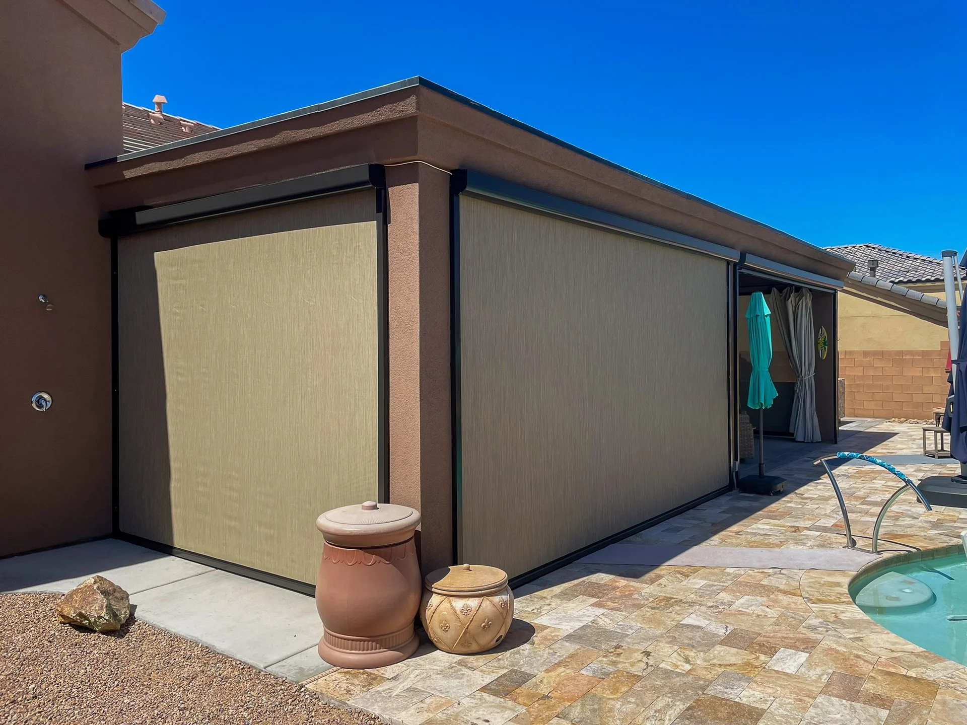 Backyard with a pool, patio, and a covered outdoor area with curtains, umbrellas, and outdoor furniture.