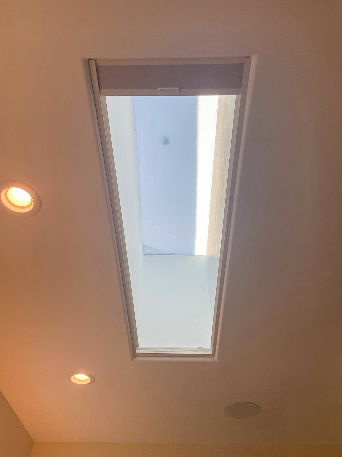 Ceiling with a rectangular skylight, recessed lighting, and a small circular vent.