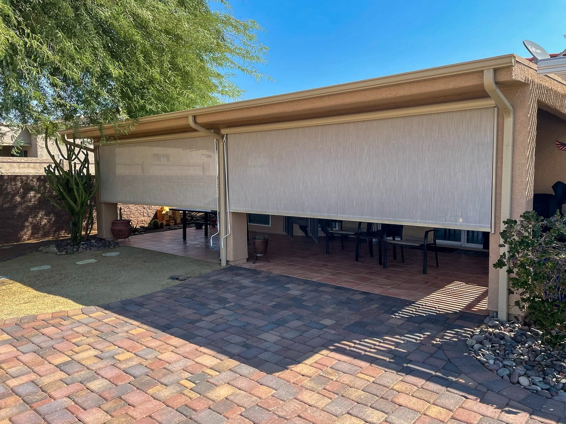 Backyard patio with retractable screens, brick pavers, sidewalk, plants, trees, and outdoor seating.