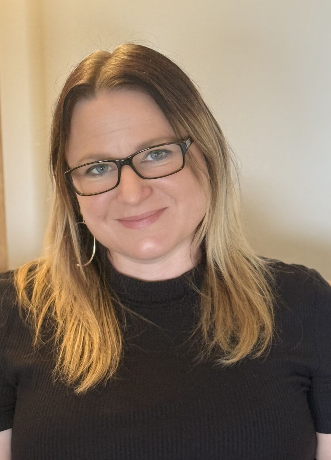 A profile picture of Claudia Bakewell, wearing glasses and a black top, smiling at the camera.